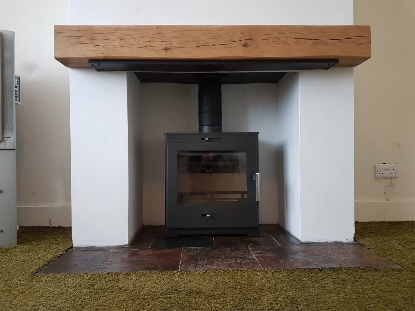 Wood burning stove installation Windsor, steel stove beneath a solid oak beam mantel