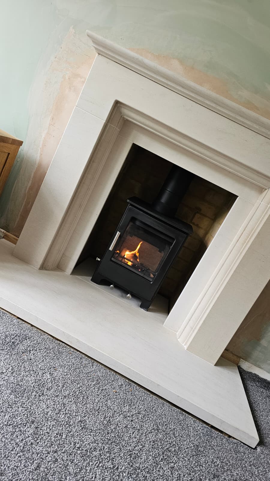 Inset cassette stove seated flush inside a limestone surround