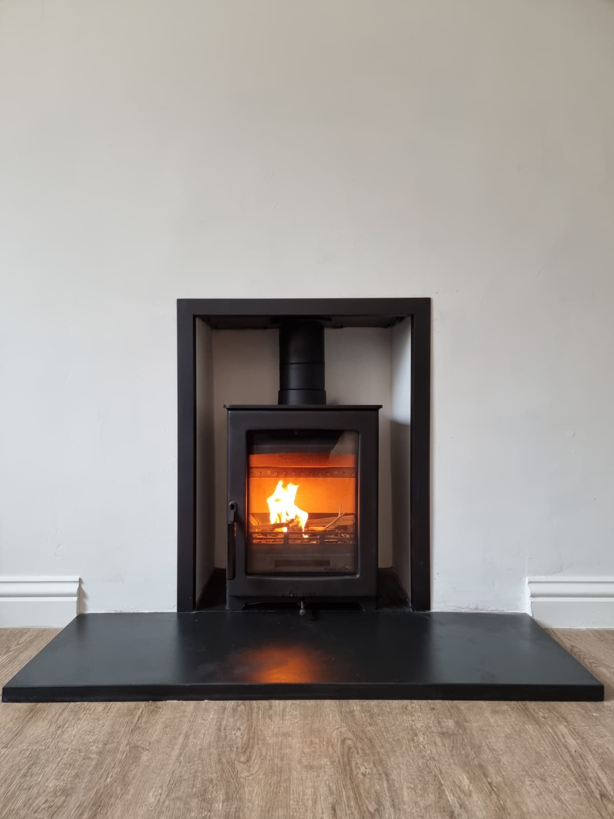 Flush inset cassette stove framed by a black tiled chamber