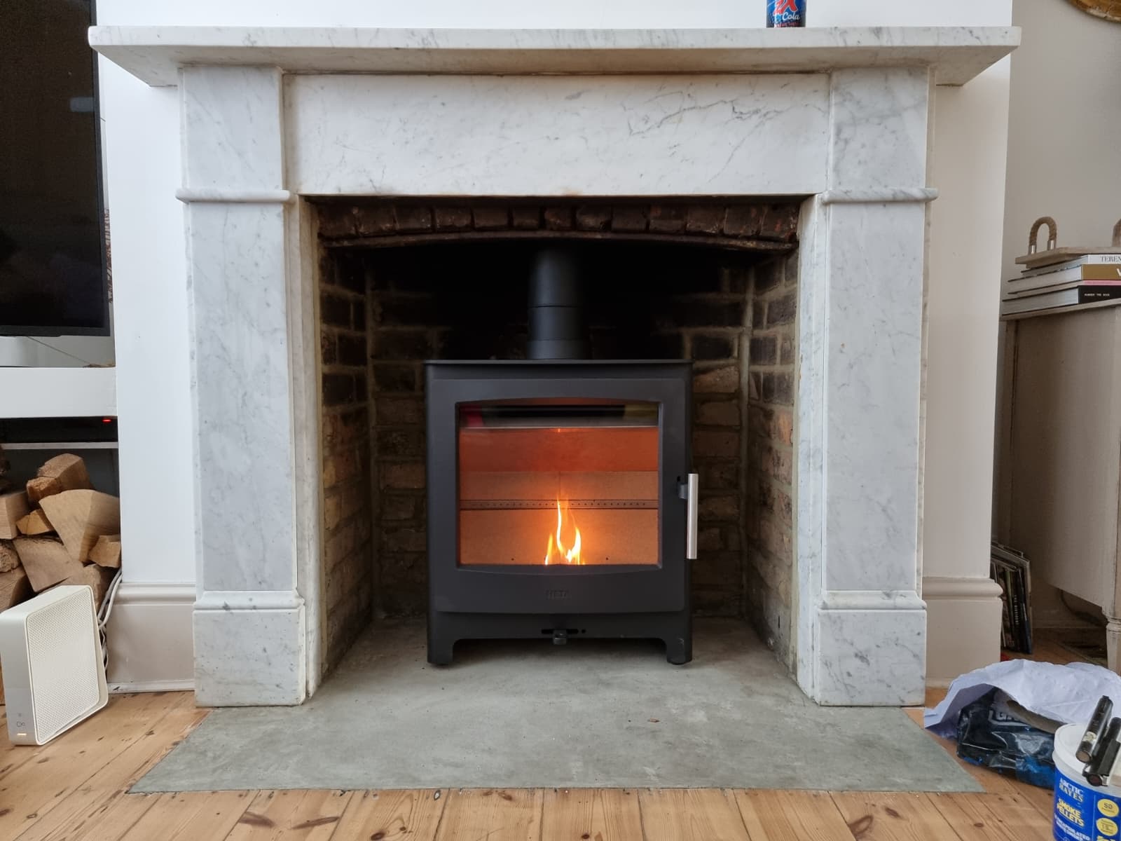 Contemporary wood burning stove set into a white marble fireplace in Windsor