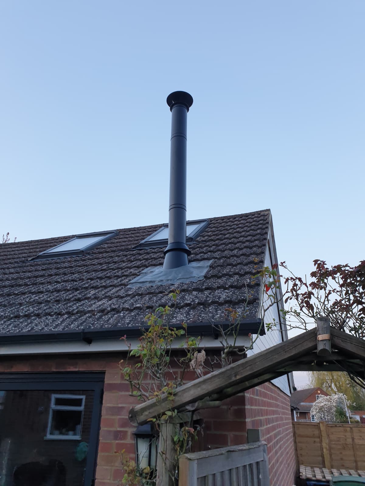 Black insulated flue pipe exiting a pitched tiled roof