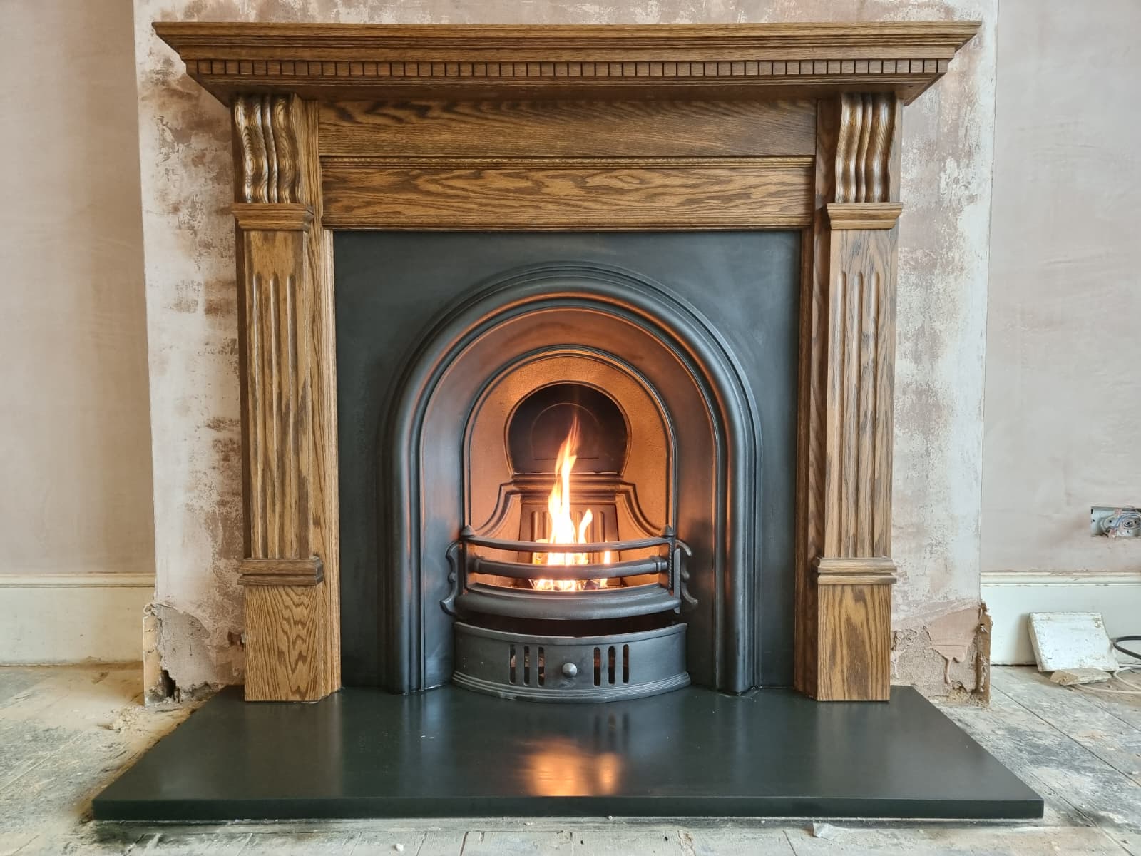 Restored ornate Victorian cast iron fireplace with original wooden mantel
