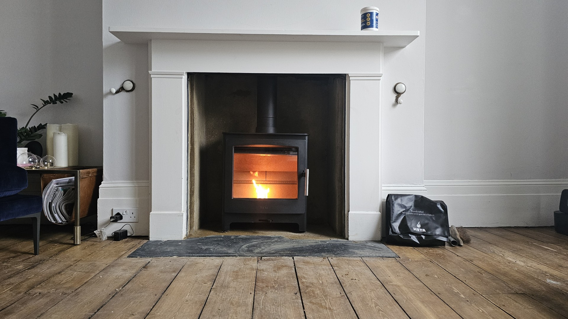 Wood burning stove alight in a white painted fireplace surround with slate hearth