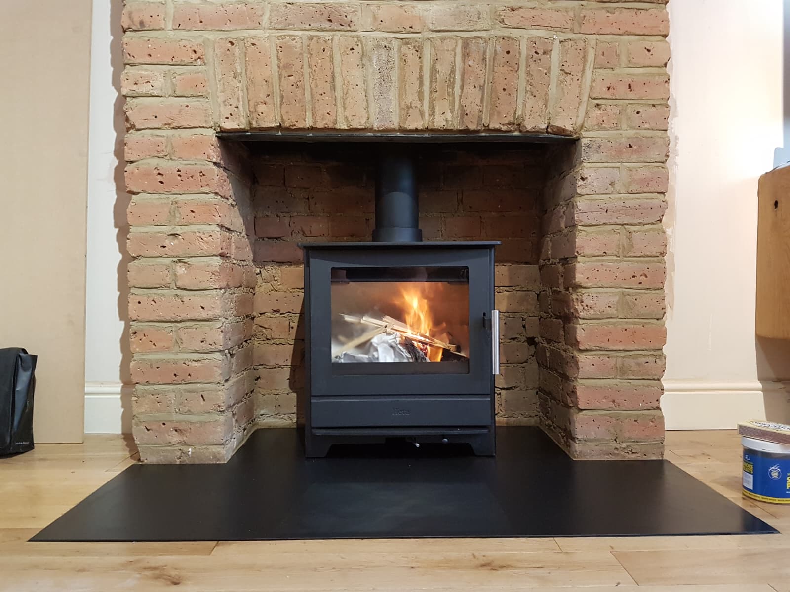 Multi-fuel stove seated in a traditional brick fireplace opening