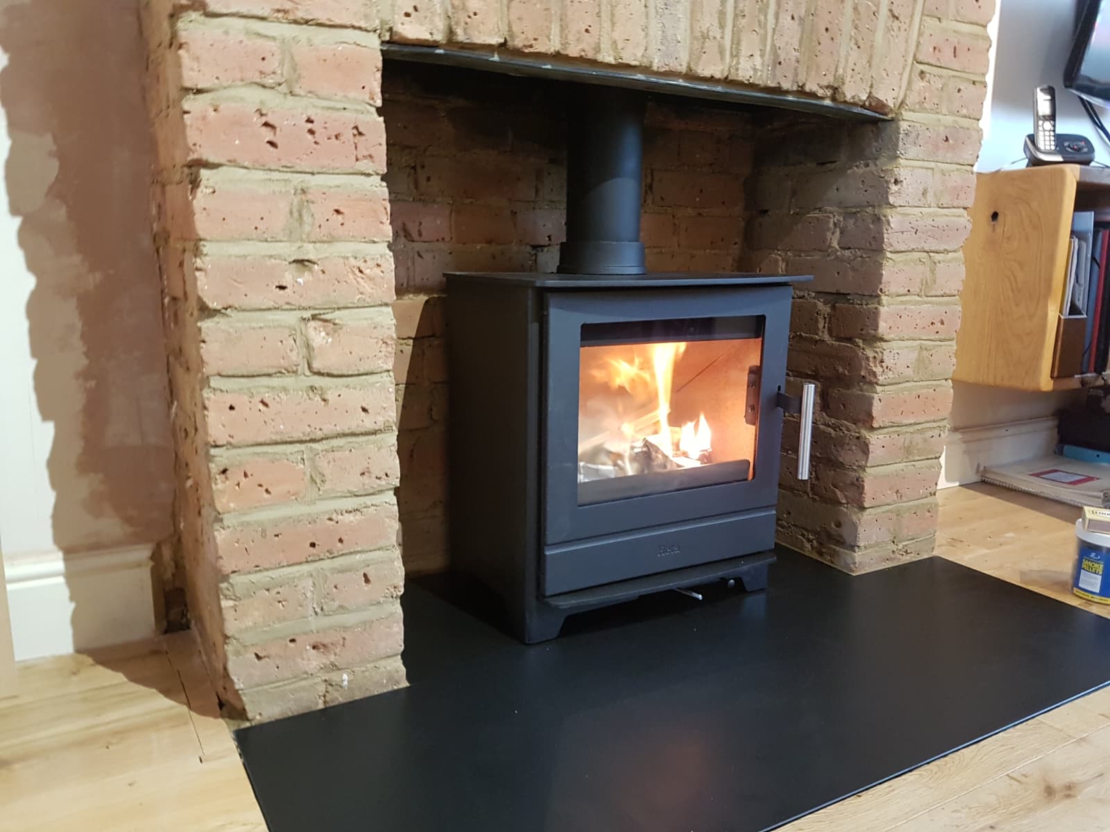 Wood burning stove installed inside a traditional brick fireplace chamber