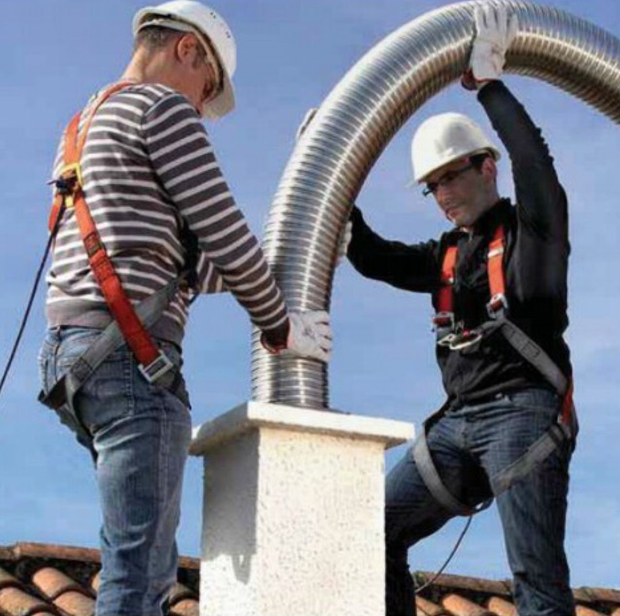 Engineers feeding a flexible stainless steel chimney liner into a chimney pot from the roof