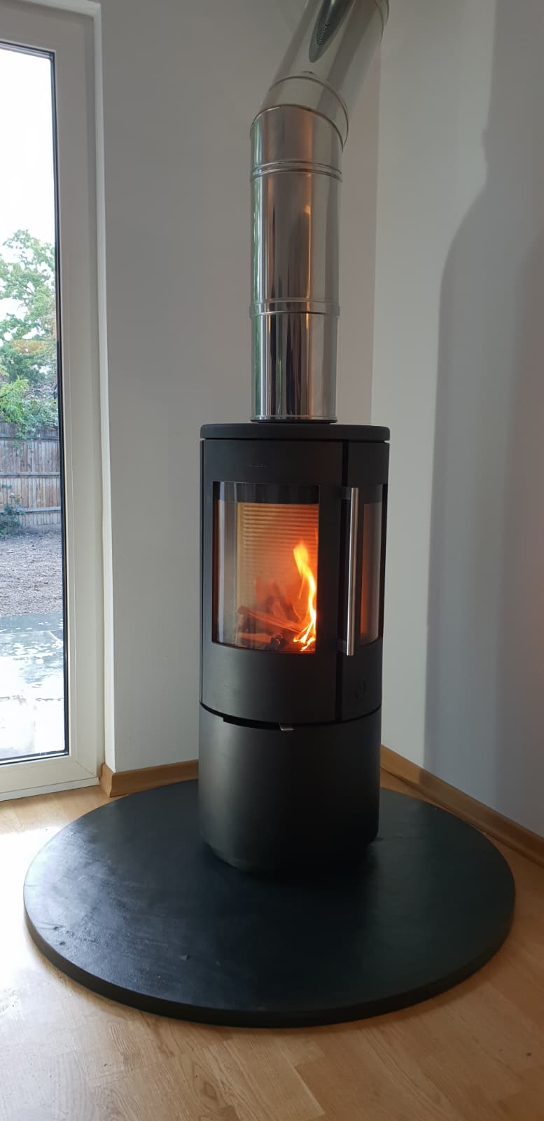 Cylindrical freestanding stove finished with a polished silver twin-wall flue