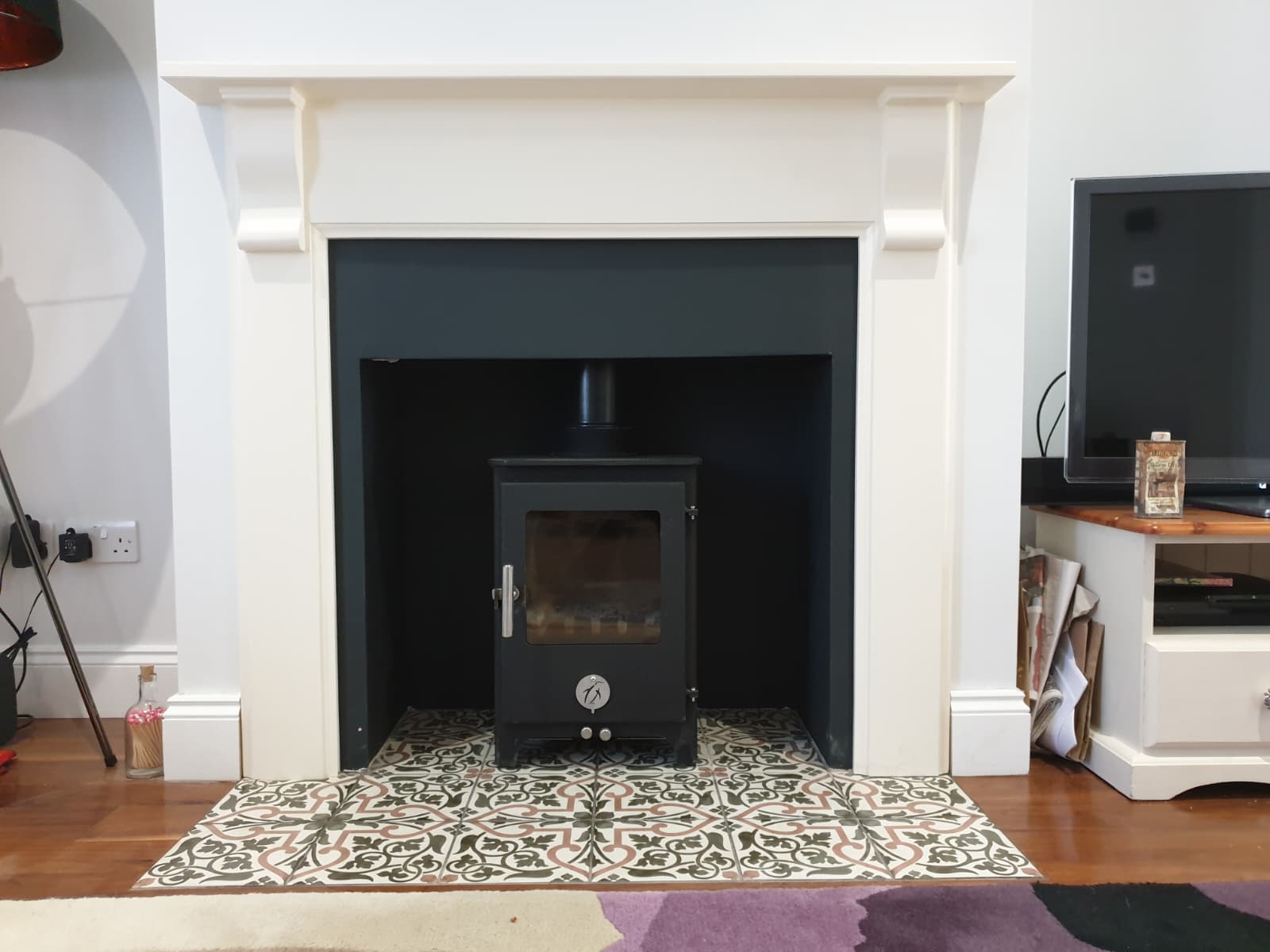 Multi-fuel stove installed in a painted surround with patterned tile hearth