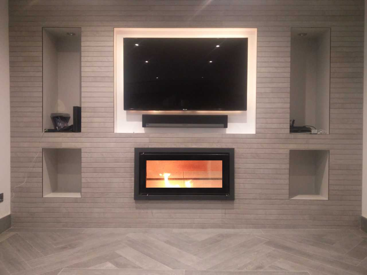 Bespoke fireplace design and install: tiled media wall with inset wood burning fire, TV recess and alcove niches