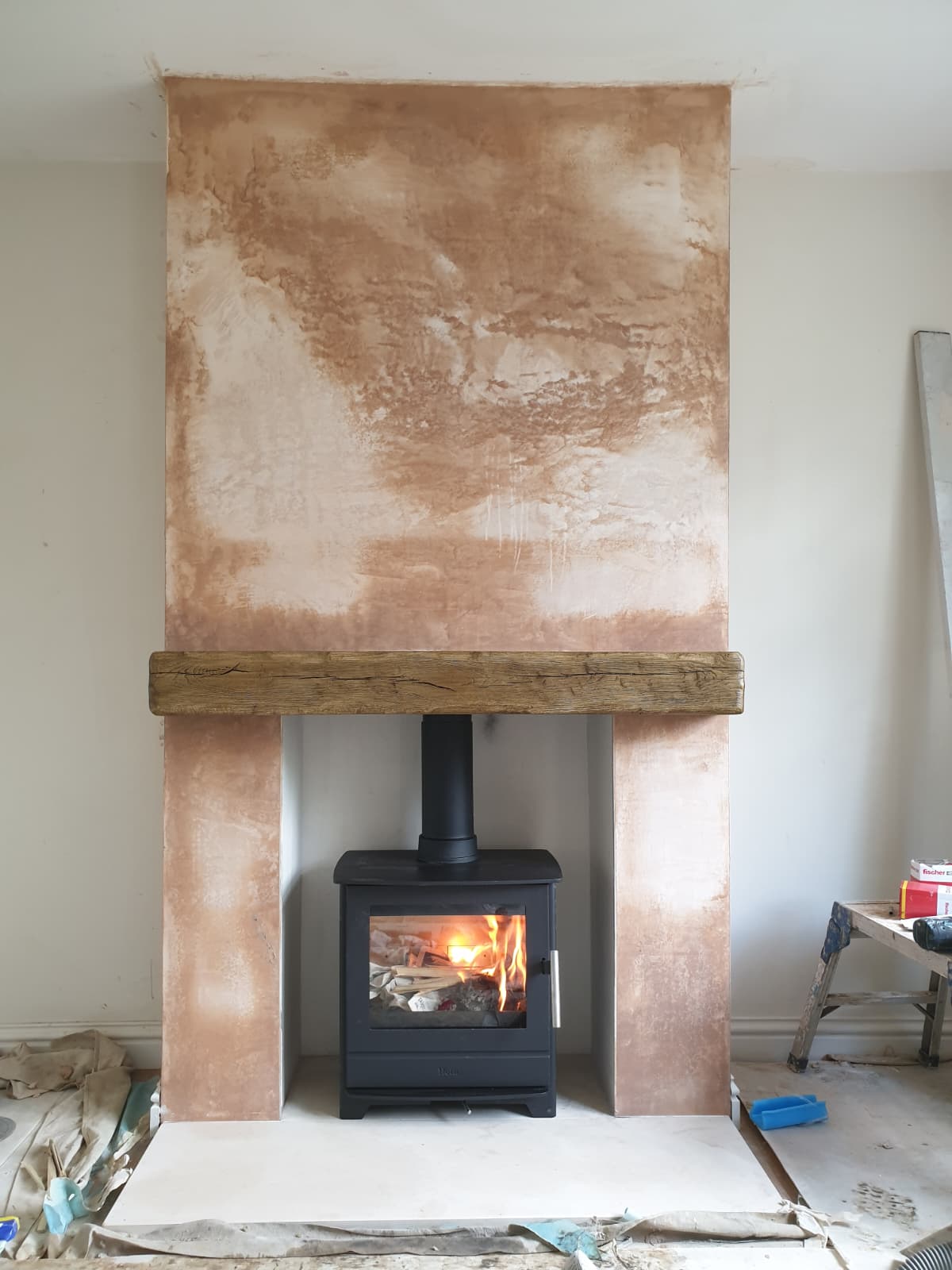 Modern Ecodesign wood burning stove installed in a full-height chimney breast with an oak beam mantel