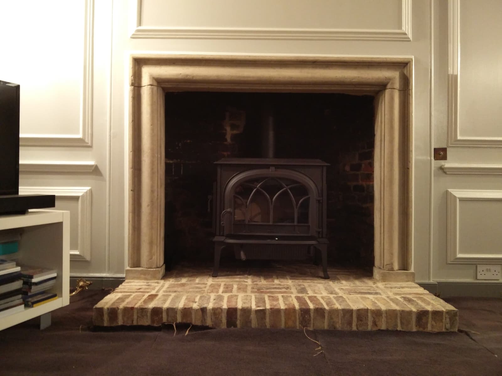 Restored stone mantel with brick hearth and cast iron stove in a heritage home