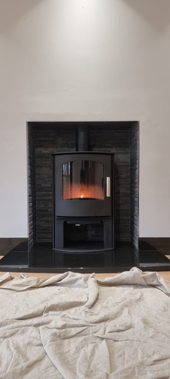 Compact inset stove fitted flush in a dark tile chamber
