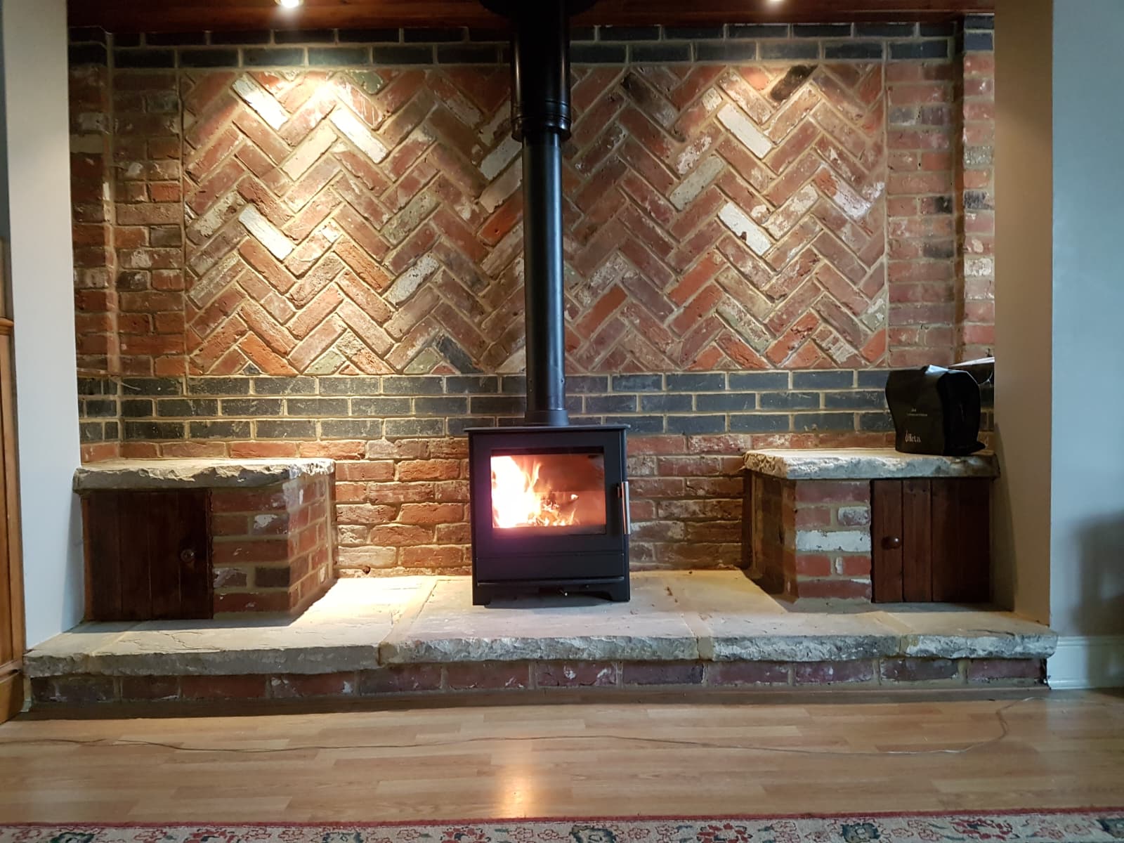 Bespoke fireplace design: herringbone brick feature wall with wood burning stove